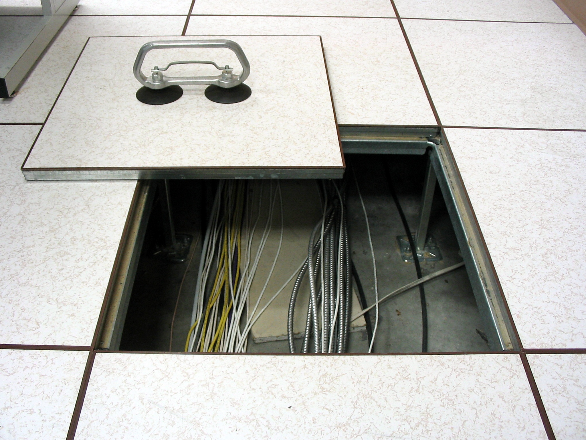 A tile being lifted on a raised floor